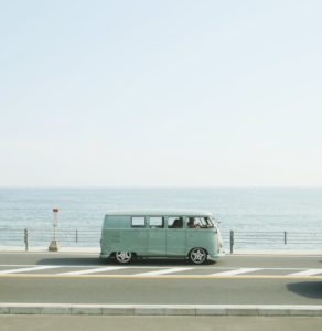 van parked beside the road near handrail and ocean